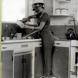 The image is showing Barbara Roscoe doing her hair and cooking.